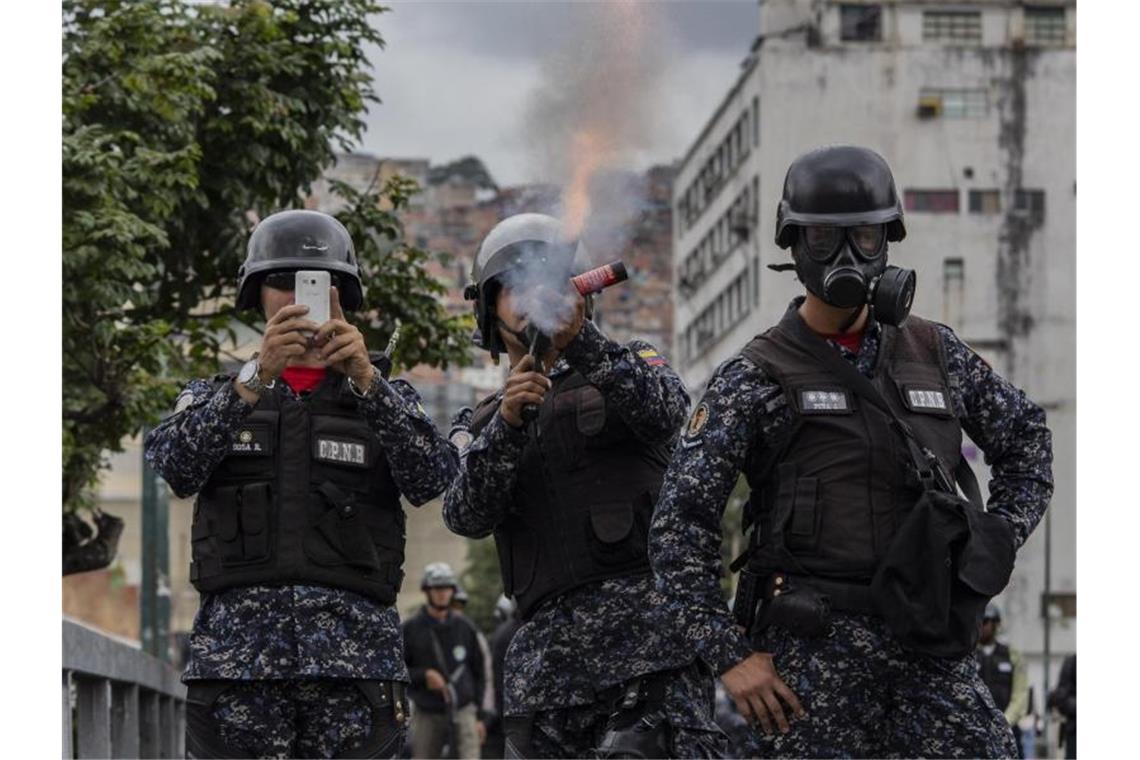 Venezuelas Präsident Maduro stellt den USA ein Ultimatum Ein Soldat feuert in Caracas mit Tränengas auf Demonstranten, während ein zweiter die Szene mit einem Handy aufnimmt. Inmitten der eskalierenden politischen Krise in Venezuela hat sich der Präsident des entmachteten Parlaments, Juan Guaidó, zum Staatschef erklärt. Foto: Rayner Pena