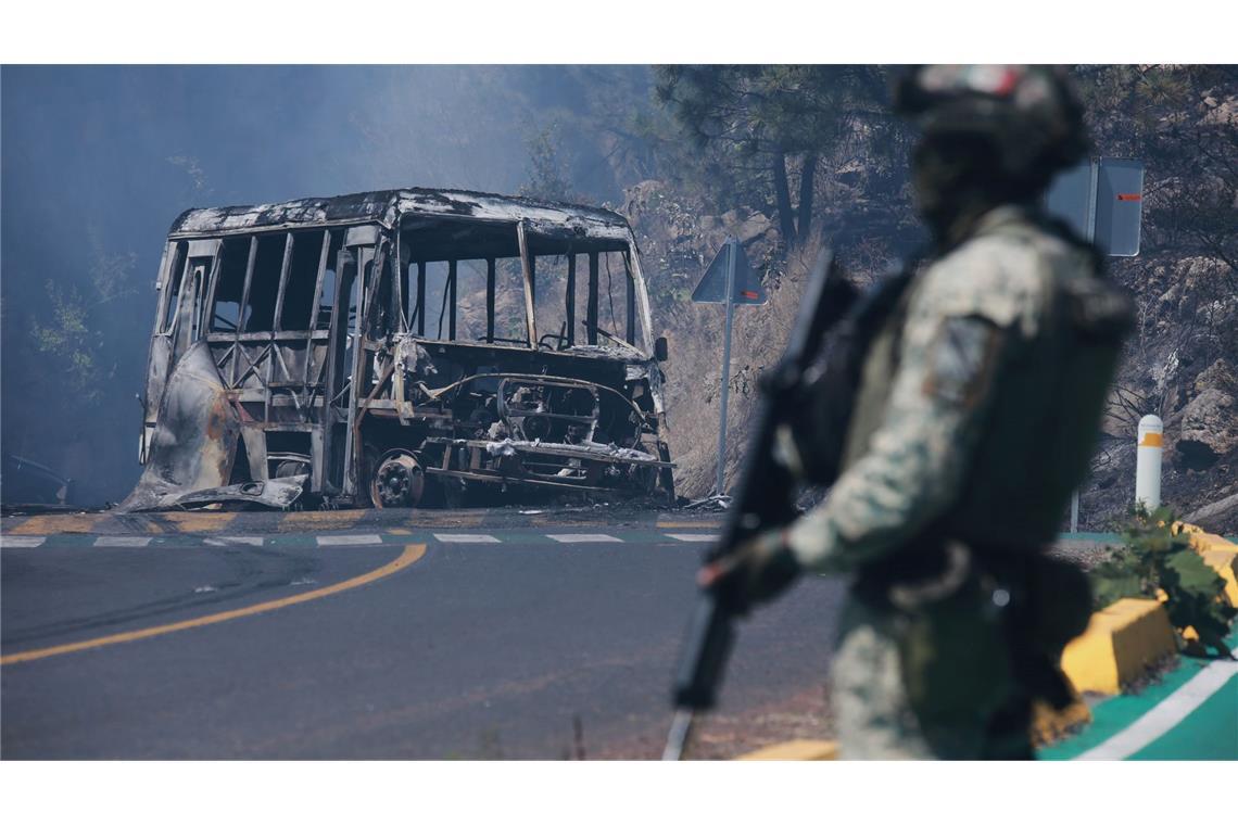 Ein Soldat steht neben einem ausgebrannten Bus, der nach dem Tod von Mexikos mächtigstem Drogenboss Nemesio Oseguera Cervantes, aka "El Mencho", in Cointzio in Brand gesetzt wurde.