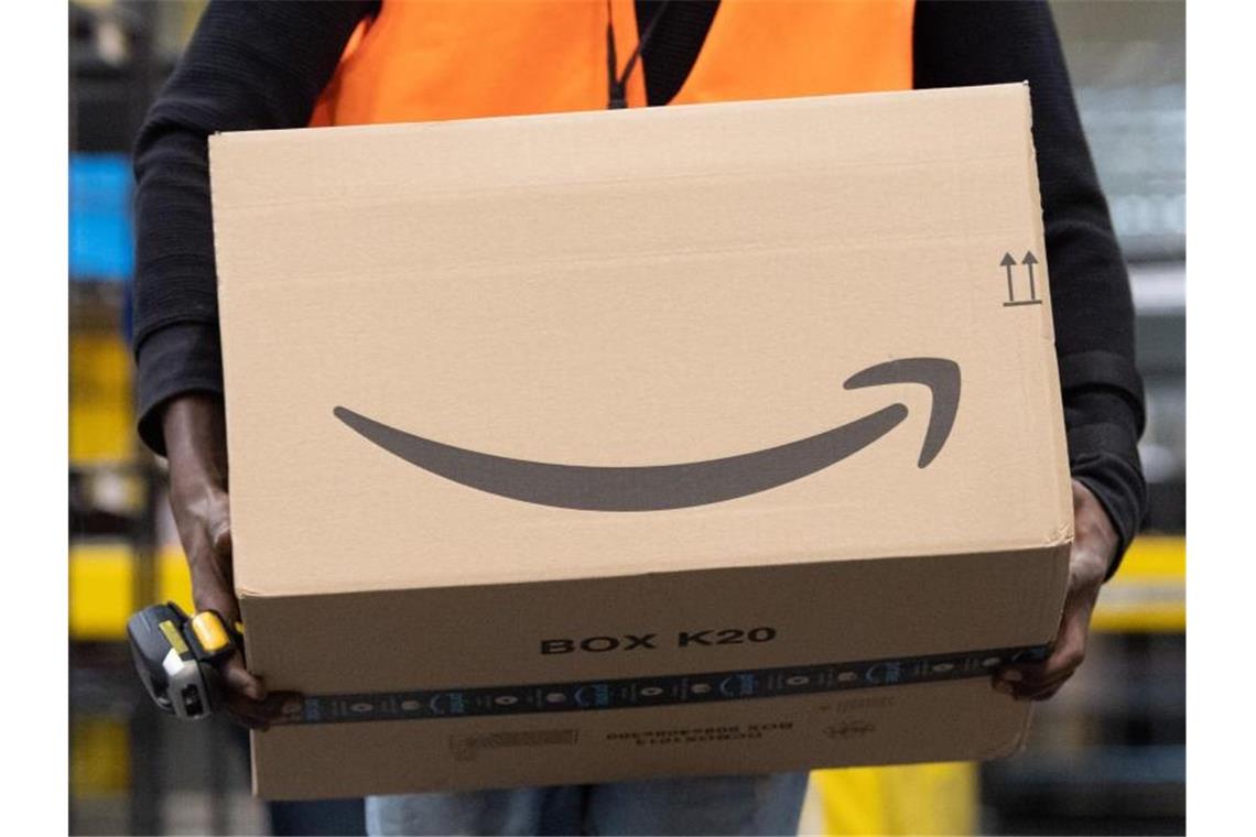 Ein Sortiermitarbeiter von Amazon trägt in einem Verteilzentrum ein Paket. Verbraucherschützer sehen die zunehmende Marktmacht großer Online-Plattformen wie Amazon mit Sorge. Foto: Sebastian Kahnert/dpa-Zentralbild/dpa