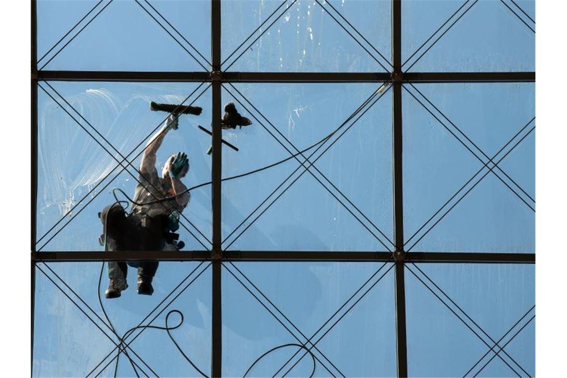 Ein spezialisierter Glas- und Gebäudereiniger putzt in 27 Metern Höhe ein Dach. Foto: Robert Michael/zb/dpa