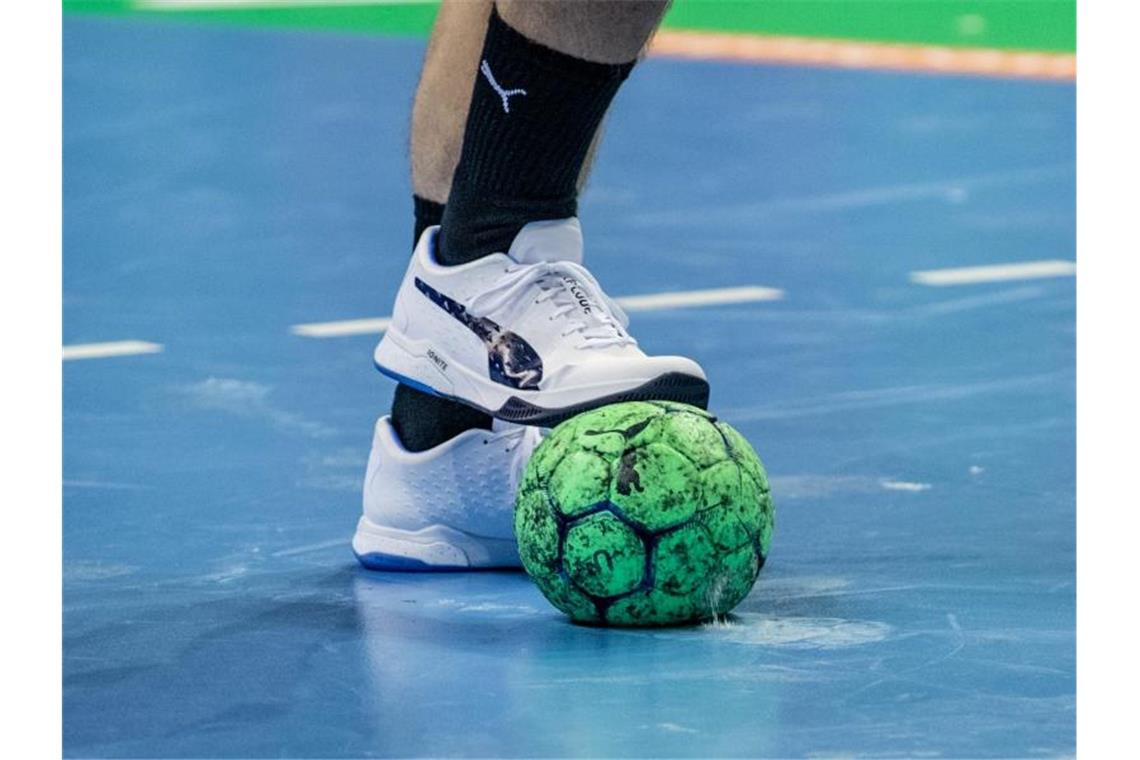 Ein Spieler hält einen Handball mit dem Fuß fest. Foto: Andreas Gora/dpa/Symbolbild