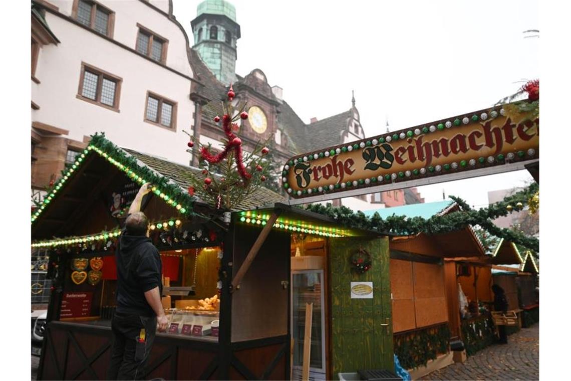 Weihnachtsmarktsaison beginnt in Freiburg Ein Standbesitzer kontrolliert auf dem Weihnachtsmarkt am Rathausplatz eine Lampenkette. Foto: Patrick Seeger/dpa