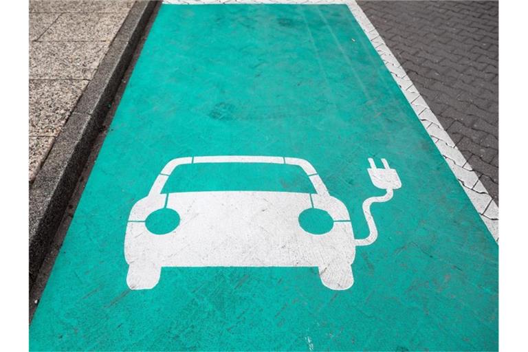Ein stilisiertes Auto auf grünen Grund markiert einen Parkplatz mit Ladesäule für Elektrofahrzeuge. Foto: Jan Woitas/zb/dpa