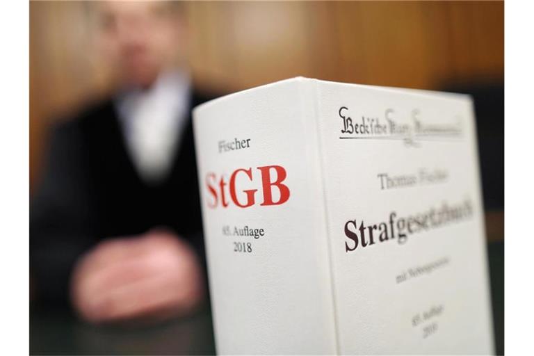 Ein Strafgesetzbuch (StGB) steht in einem Gericht auf der Richterbank. Foto: Oliver Berg/dpa/Archivbild