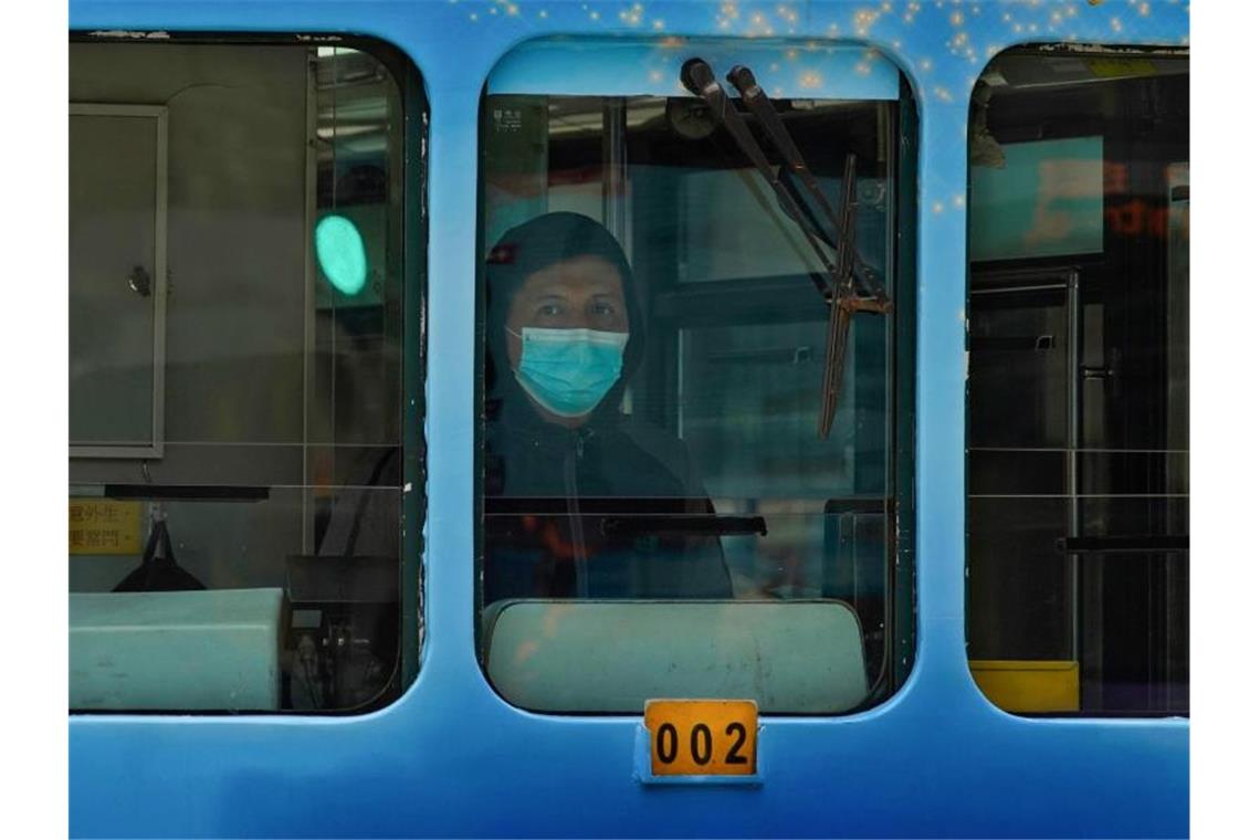 Ein Straßenbahnfahrer in Hongkong trägt eine Maske. Foto: Vincent Yu/AP/dpa