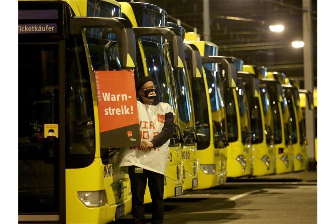 Ein streikender Busfahrer der Ruhrbahn klebt ein Plakat "Warnstreik" an einen Bus. Foto: Roland Weihrauch/dpa