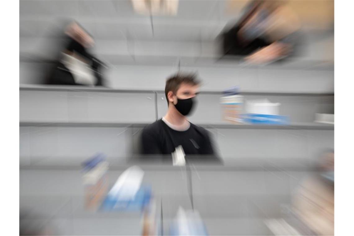 Ein Student sitzt in einer Begrüßungsveranstaltung für Studierende im ersten Semester. Foto: Sebastian Gollnow/dpa/Archivbild