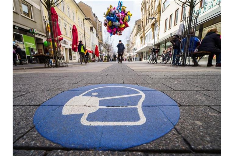 Ein Symbol zur Maskenpflicht ist auf dem Pflaster der Fußgängerzone in der Offenbacher Innenstadt aufgebracht. (Archivbild). Foto: Frank Rumpenhorst/dpa
