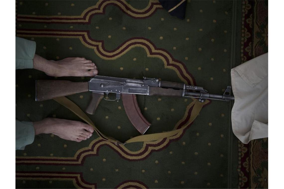 Schily und Fischer werfen USA Versagen in Afghanistan vor Ein Taliban-Kämpfer nimmt seine Kalaschnikow von Typ AK-47 zum Beten mit in eine Moschee. Foto: Felipe Dana/AP/dpa