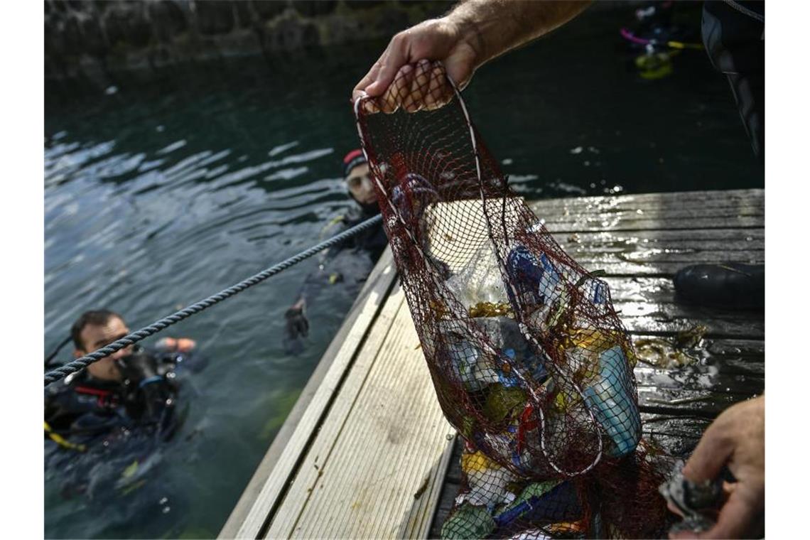 Ein Taucher hält ein Netz mit Abfällen, die er im baskischen Dorf Bermeo aus dem Meer entzogen hat. Foto: Alvaro Barrientos/AP/dpa