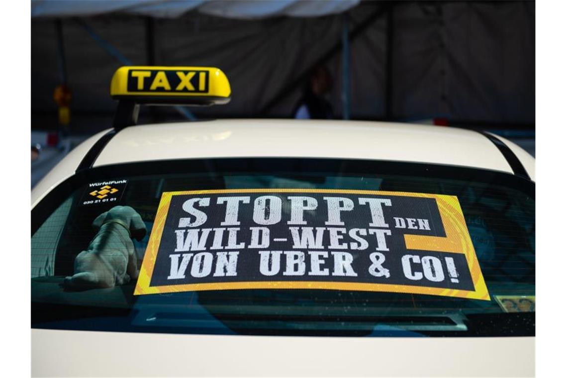 Uber startet neuen Limousinen-Service „Uber Premium“ Ein Taxi mit einem Protestschild am Rand einer Demonstration gegen Uber. Foto: Lisa Ducret/dpa