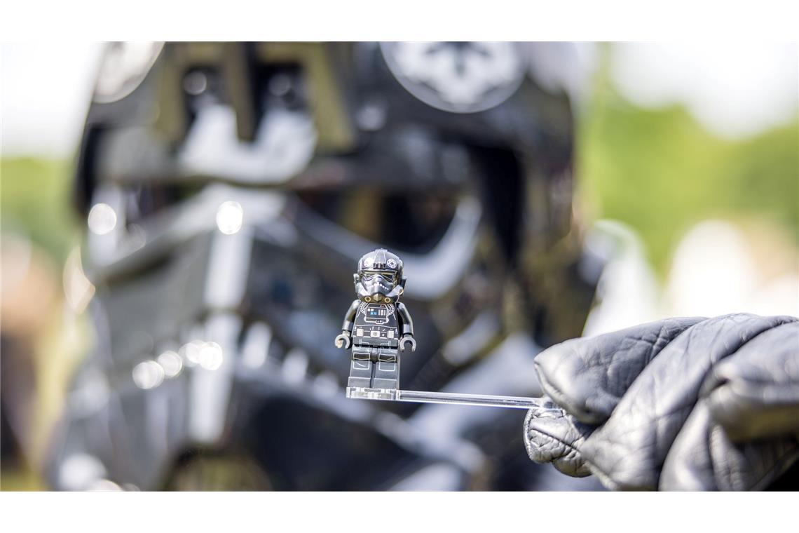 Bilder des Tages Ein Teilnehmer des Elbenwald Festivals, als Mitglied der Stormtroopers verkleidet, hält eine Figur seiner Rolle vor seinen Kopf.