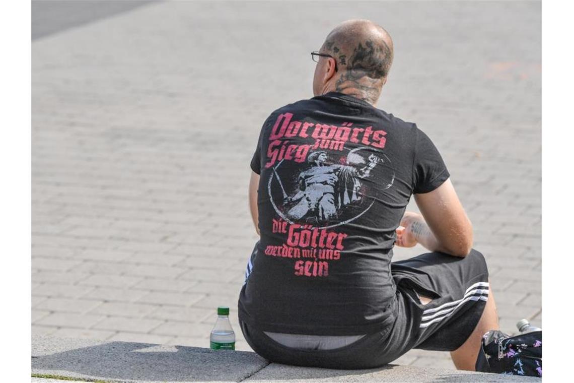 Ein Teilnehmer des Wahlkampfauftakts sitzt auf einer Treppe vor der Cottbusser Stadthalle. Foto: dpa-Zentralbild