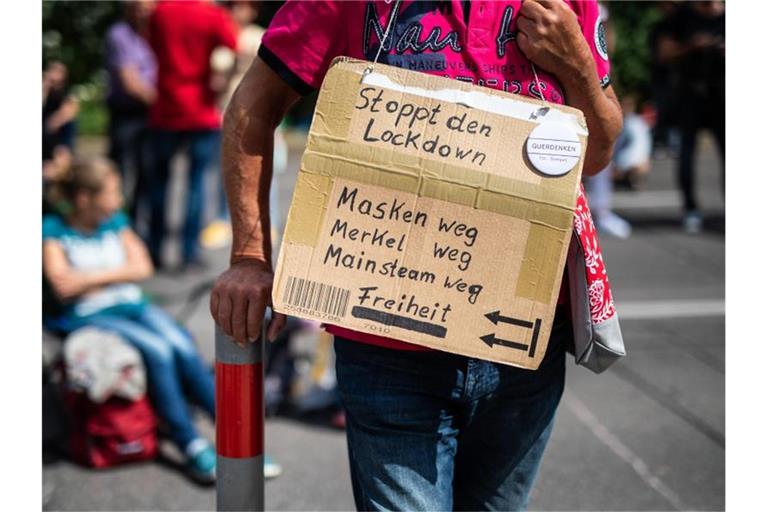 Ein Teilnehmer einer „Querdenker 711“-Demo in Stuttgart fordert auf seinem Plakat unter anderem den Stopp des Lockdowns. Foto: Christoph Schmidt/dpa/Archivbild