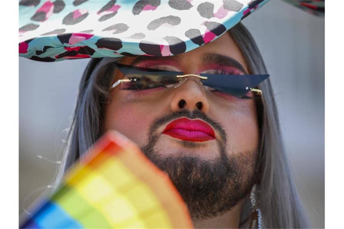 Ein Teilnehmer fächert sich bei der jährlichen Pride Parade Luft mit einem regenbogenfarbenen Fächer zu. Foto: Ariel Schalit/AP/dpa