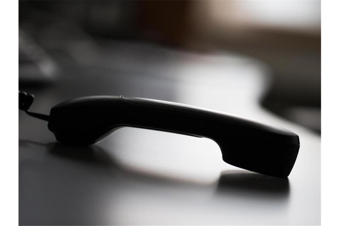 Ein Telefonhörer liegt auf einem Tisch. Foto: Rolf Vennenbernd/dpa/Illustration