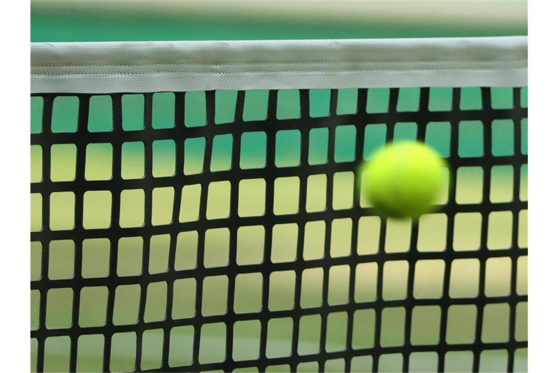 Ein Tennisball fliegt in ein Netz. Foto: picture alliance / Friso Gentsch/dpa/Symbolbild