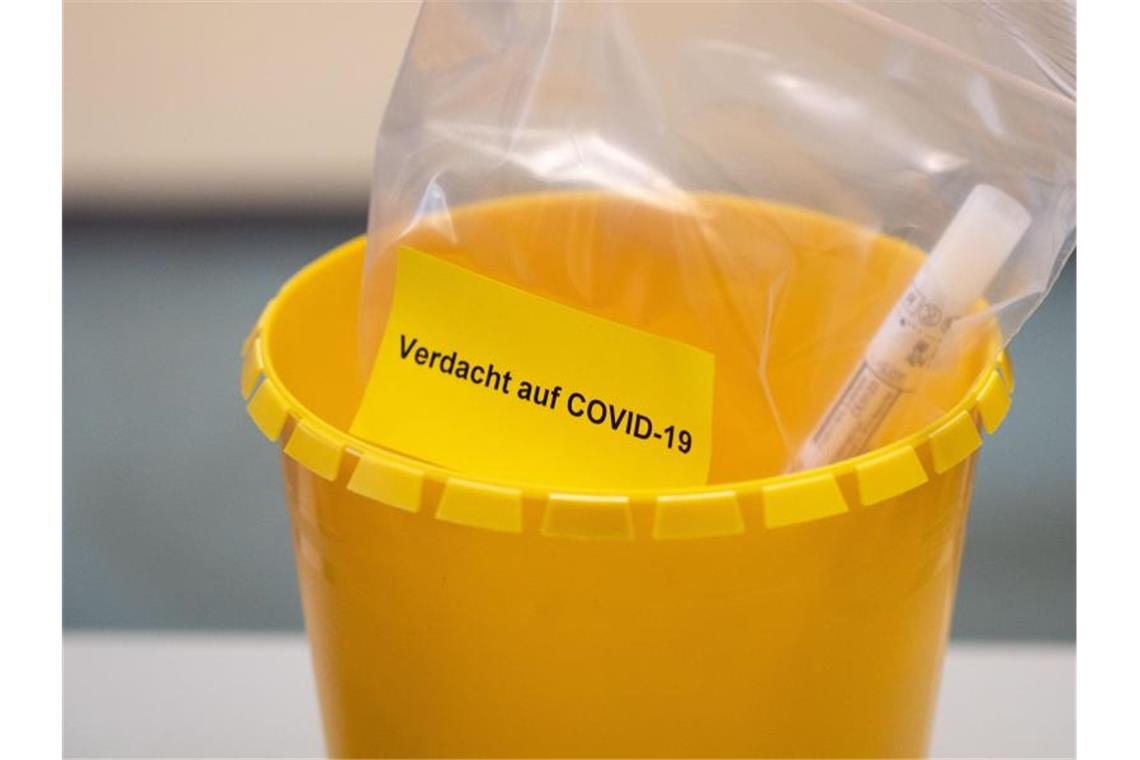 Ein Teströhrchen liegt in einer Tüte mit der Aufschrift „Verdacht auf COVID-19“. Foto: Marius Becker/dpa
