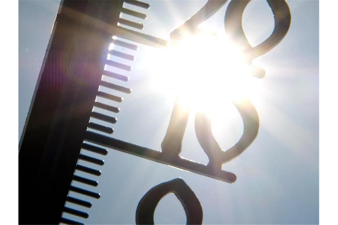Ein Thermometer wird gegen die Sonne gehalten. Foto: picture alliance / dpa/Archivbild