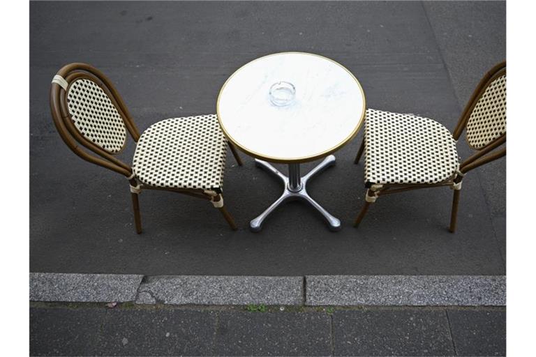 Ein Tisch mit zwei Stühlen steht auf der Töngesgasse in der Frankfurter Innenstadt vor einem Café. Foto: Arne Dedert/dpa