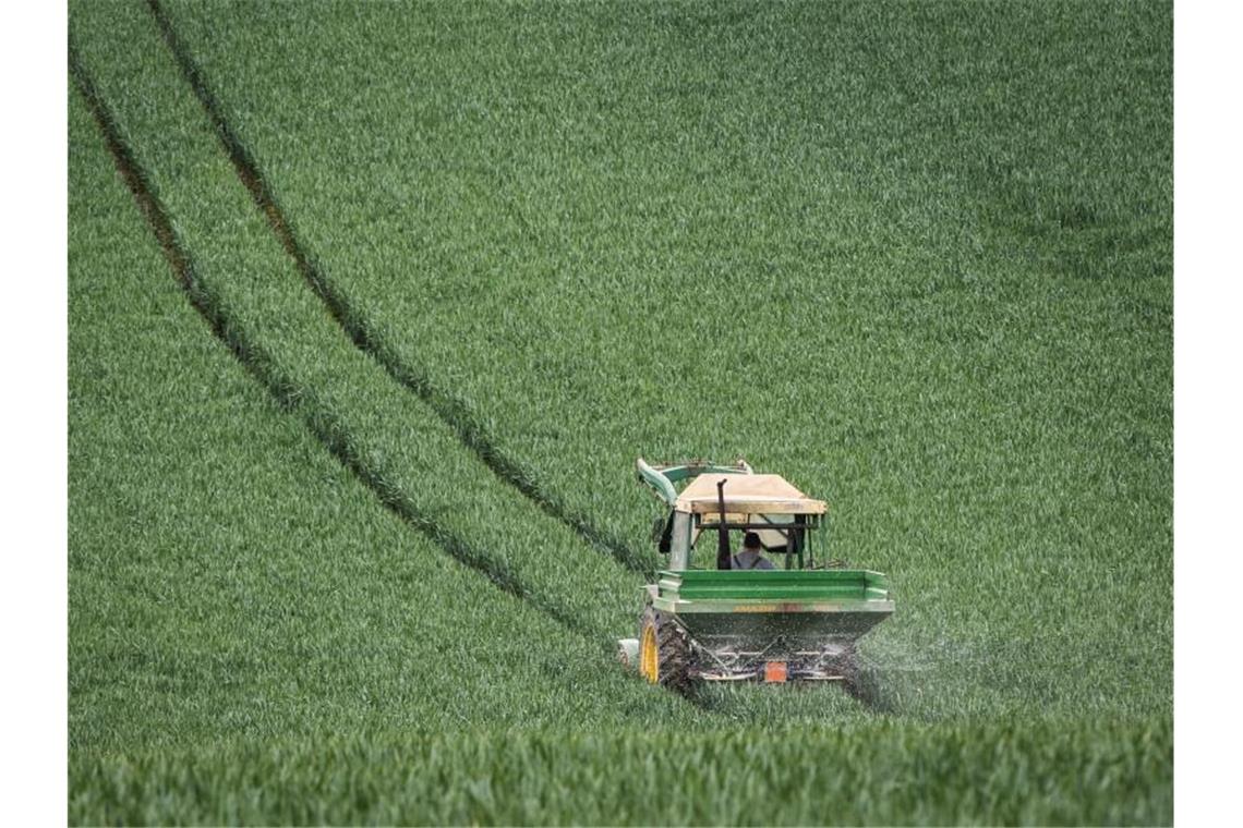 Ein Traktor auf einem ein noch grünen Getreidefeld. Foto: Frank Rumpenhorst/dpa