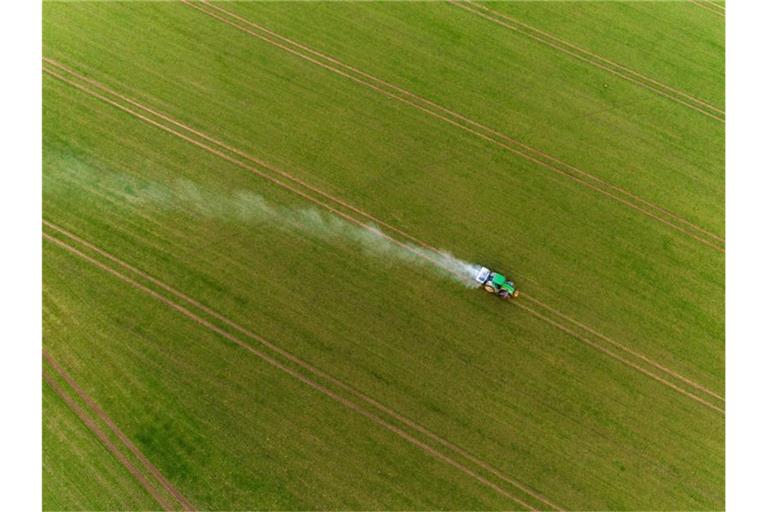 Ein Traktor fährt bei Gammelin über einen Acker und verteilt mit einem Streuer Pflanzendünger. Foto: Jens Büttner/dpa-Zentralbild/dpa
