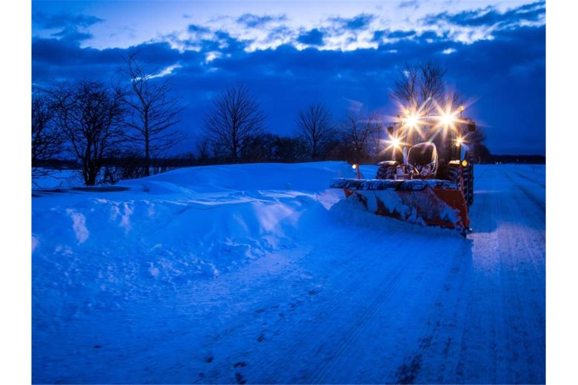 Mindestens bis zum Wochenende bleibt es kalt Ein Traktor mit Schneepflug räumt am frühen Morgen eine teilweise zugewehte Straße im Norden der Ostseeinsel Rügen. Foto: Jens Bttner/dpa-Zentralbild/dpa