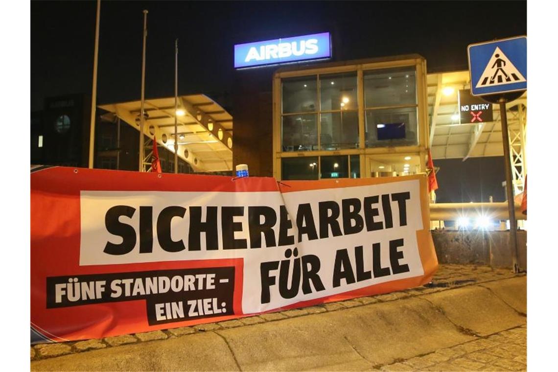 Ein Transparent mit der Aufschrift „Sichere Arbeit für Alle“ hängt vor den Werkstoren des Flugzeugherstellers Airbus in Hamburg-Finkenwerder. Foto: Bodo Marks/dpa