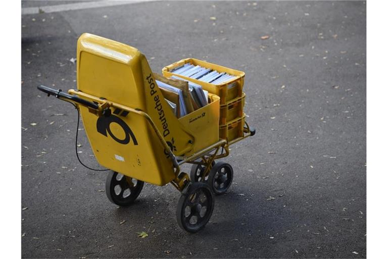 Ein Trolley eines Zustellers der Deutschen Post steht auf der Straße. Verdi fordert 5,5 Prozent mehr Geld für 140.000 Beschäftigte, die Post hat bisher noch kein Angebot vorgelegt. Foto: Lino Marcel Mirgeler/dpa