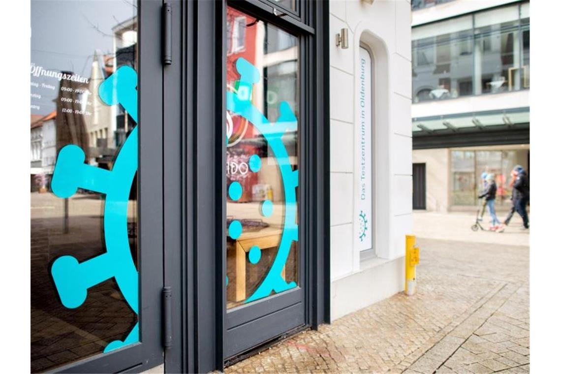 Ein überdimensionales Coronavirus klebt am Fenster eines Cafés in der Oldenburger Innenstadt, das derzeit als Testzentrum genutzt wird. Foto: Hauke-Christian Dittrich/dpa