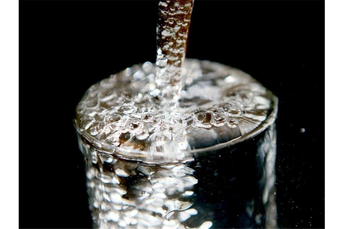 Wasser muss wegen Bakterien abgekocht werden Ein überlaufendes Glas, in das Trinkwasser läuft. Foto: Oliver Berg/dpa/Illustration
