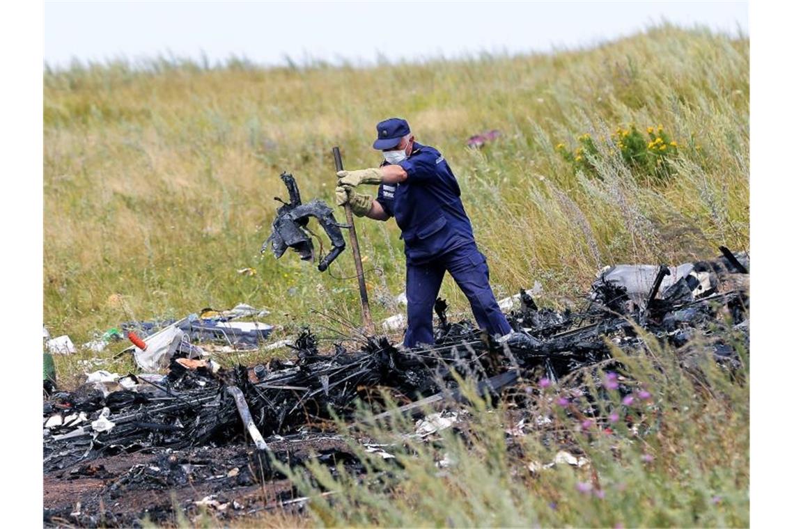 Ein ukrainischer Arbeiter untersucht im Juli 2014 an der Absturzstelle von MH17 Wrackteile der Maschine. Foto: Robert Ghement/epa