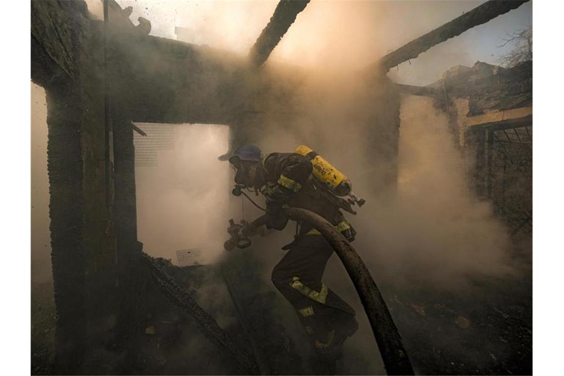 Ein ukrainischer Feuerwehrmann bei Löscharbeiten in einem nach russischen Angriffen zerstörten Haus in Kiew. Foto: Vadim Ghirda/AP/dpa