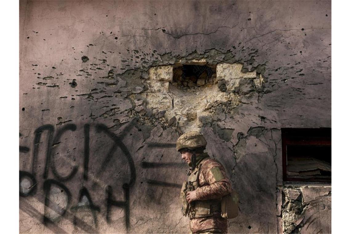 Nato befürchtet „vollständigen Angriff“ auf Ukraine Ein ukrainischer Soldat geht an einem Gebäude vorbei, das von einer großkalibrigen Mörsergranate in der Region Luhansk getroffen wurde. Foto: Vadim Ghirda/AP/dpa