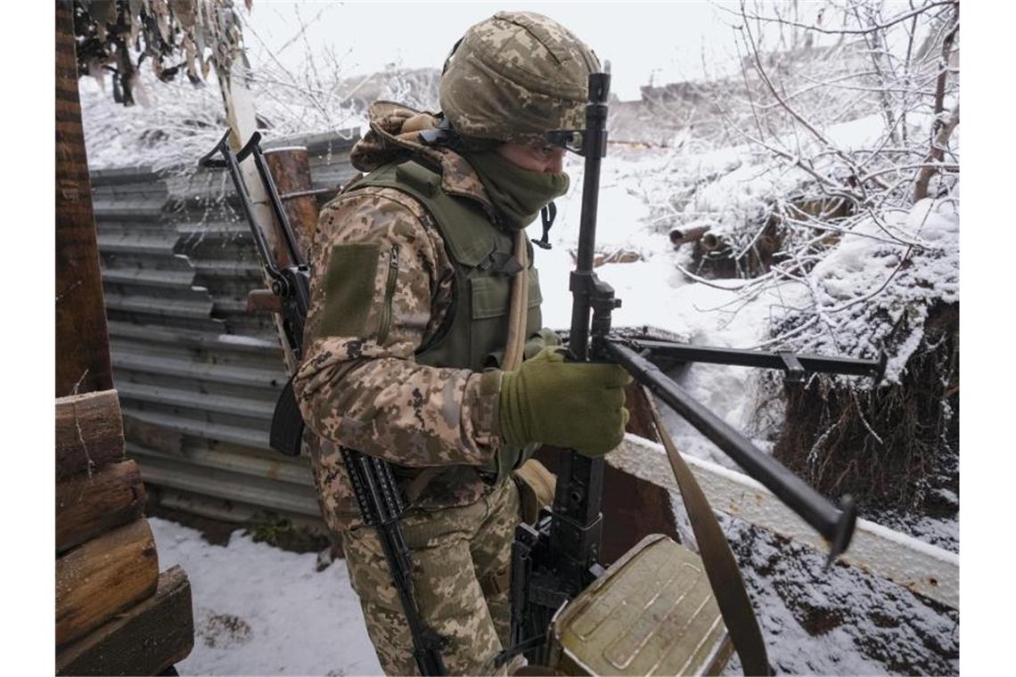 Scholz reist in die USA - Rufe nach Waffenlieferungen lauter Ein ukrainischer Soldat trägt in einem Graben an der Frontlinie in der Ostukraine ein schweres Maschinengewehr. Foto: Vadim Ghirda/AP/dpa