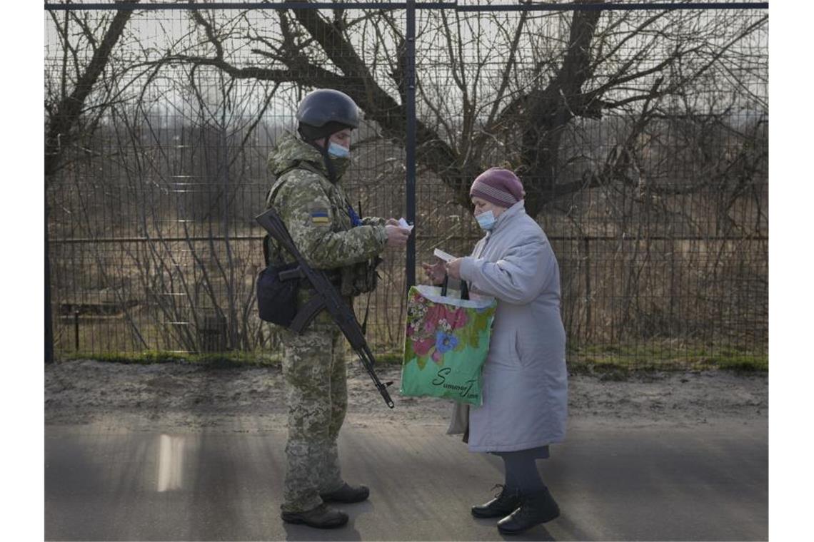 Ostukraine: Russland kritisiert Aussagen von Guterres Ein ukrainischer Soldat überprüft die Papiere einer älteren Frau am Grenzübergang in der Region Luhansk. Foto: Vadim Ghirda/AP/dpa