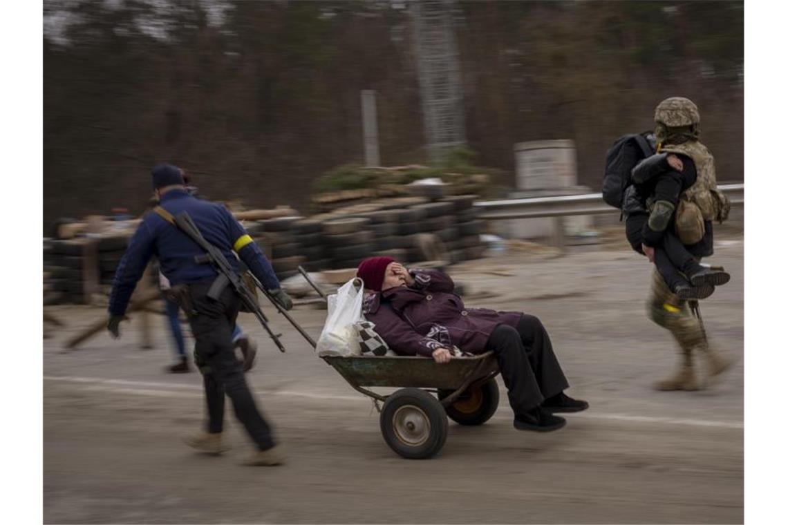 Russland setzt Angriff auf Mariupol fort Ein ukrainischer Soldat und ein Milizionär helfen einer fliehenden Familie bei der Überquerung des Flusses Irpin in den Außenbezirken von Kiew. Foto: Emilio Morenatti/AP/dpa