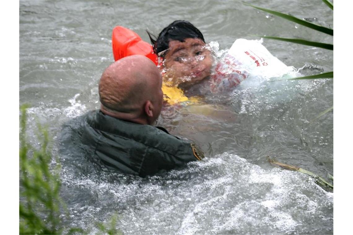 Trump stößt nach Einigung mit Mexiko erneut Drohungen aus Ein US-Grenzschutzbeamter hilft einem Jungen aus Honduras, nachdem er von einem Floß in den Grenzfluss Rio Grande gefallen ist. Jedes Jahr fliehen Hunderttausende Menschen vor Gewalt und Armut in Mittelamerika. Foto: Bob Owen/The San Antonio Express-News