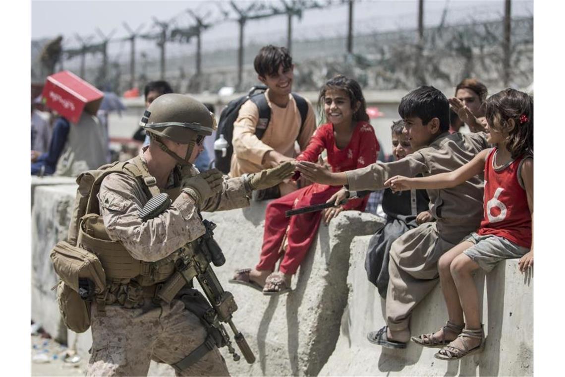 Ein US-Marine spielt mit Kindern, die während der Evakuierung am Hamid Karzai International Airport warten. Foto: Uncredited/U.S. Marine Corps/AP/dpa