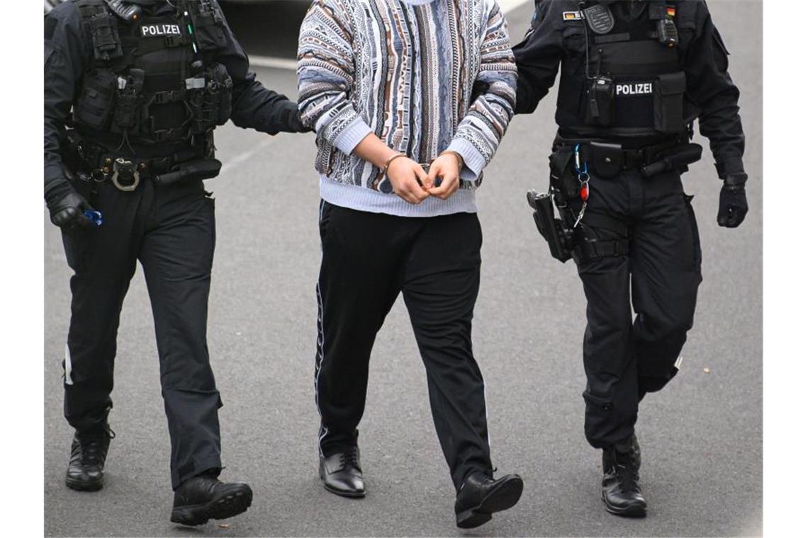 Ein verdächtiger Mann (M) im Fall um den Kunstdiebstahl im Grünen Gewölbe wird von Polizisten in das Gebäude des Oberlandesgerichts Dresden geführt. Foto: Robert Michael/dpa-Zentralbild/dpa