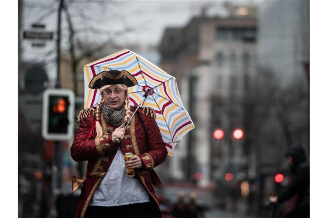 Ein verkleideter Mann geht mit Schirm über die Kö in Düsseldorf. Foto: Fabian Strauch/dpa