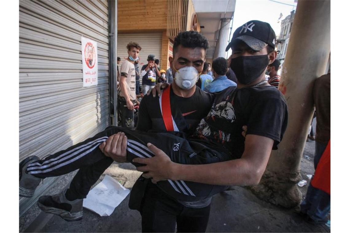 Erneut Tränengaseinsatz gegen Demonstranten im Irak Ein verletzter Demonstrant wird bei Zusammenstößen zwischen regierungsfeindlichen Demonstranten und Bereitschaftspolizei in der Al Rasheed Straße, in der Nähe des Tahrir-Platzes weggetragen. Foto: Ameer Al Mohammedaw/dpa