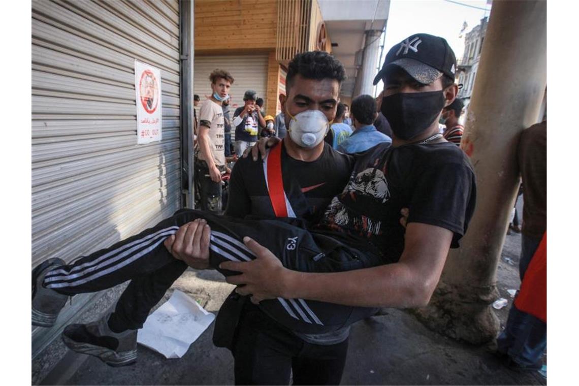 Ein verletzter Demonstrant wird bei Zusammenstößen zwischen regierungsfeindlichen Demonstranten und Bereitschaftspolizei in der Al Rasheed Straße, in der Nähe des Tahrir-Platzes weggetragen. Foto: Ameer Al Mohammedaw/dpa