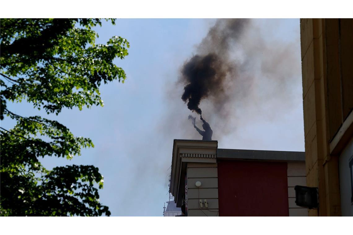 Ein Vermummter brennt auf dem Dach der Roten Flora in Hamburg Pyrotechnik ab.