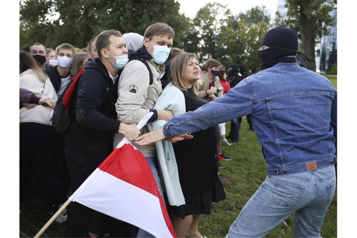 Ein vermummter, in Zivil gekleideter Polizist weist Demonstranten zurecht. Seit der Wahl vor mehr als einem Monat kommt es täglich im ganzen Land zu Protestaktionen. Foto: -/Tut.by via AP/dpa