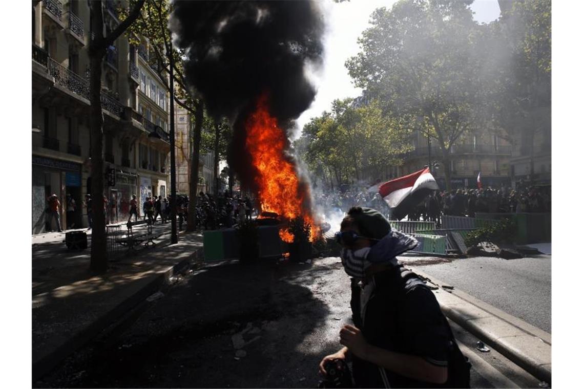 Ein vermummter Protestler geht an einer brennenden Barrikade vorbei. Foto: Thibault Camus/AP