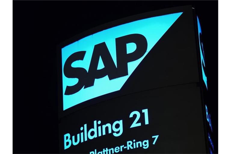 Ein von innen beleuchtetes Logo des Softwarekonzerns SAP steht vor einem Firmengebäude. Foto: Uwe Anspach/dpa/Symbolbild