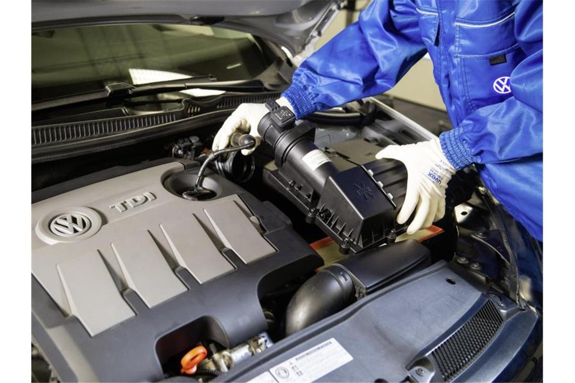 Ein VW-Mitarbeiter baut einen um einen Strömungsgleichrichter erweiterten Luftfilter in einen Dieselmotor der Typreihe EA 189 ein. Foto: Volkswagen