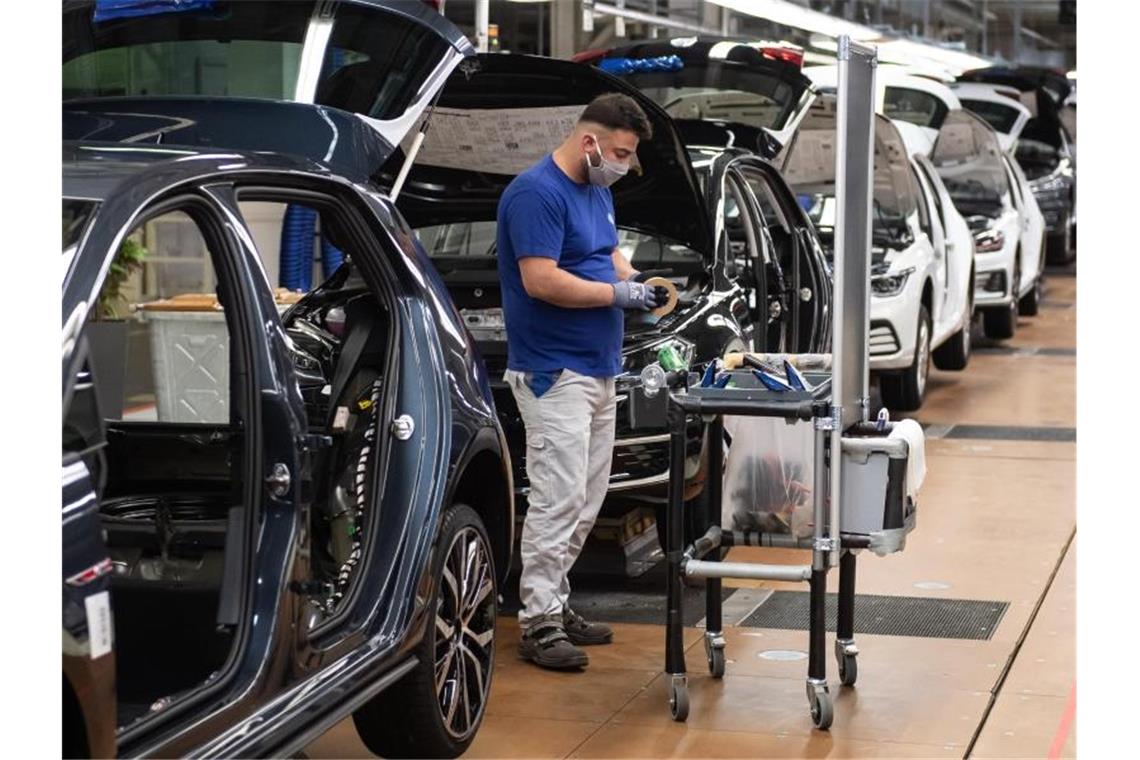 Ein VW-Mitarbeiter steht in der Produktion neben einem Auto im Werk in Wolfsburg. Foto: Swen Pförtner/dpa