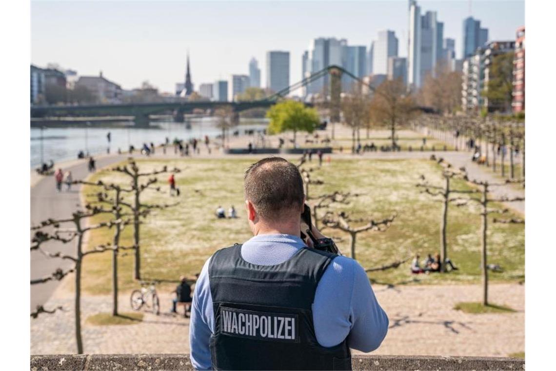 Regierung ruft zu Einhaltung der Kontaktverbote auf Ein Wachpolizist überprüft die Einhaltung der Kontaktsperre am Frankfurter Mainufer. Foto: Frank Rumpenhorst/dpa